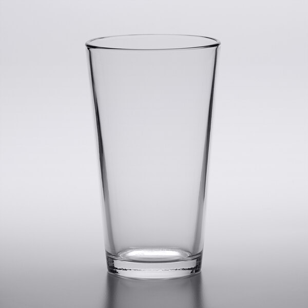An Arcoroc mixing glass with a black rim on a white surface.