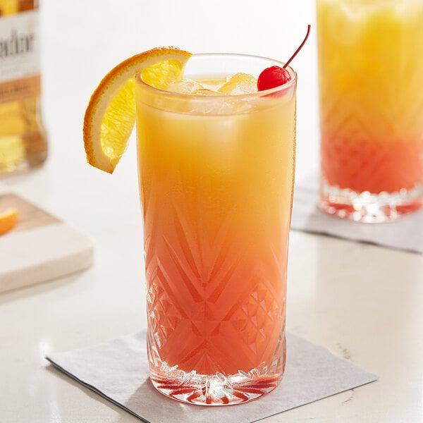 Two Arcoroc Broadway beverage glasses filled with orange and pineapple juice with a cherry and orange slice.