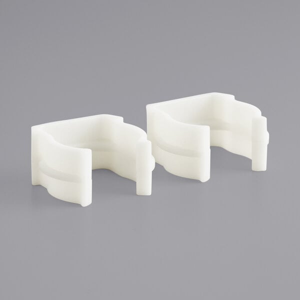 Two white plastic Lancaster Table & Seating table clips.