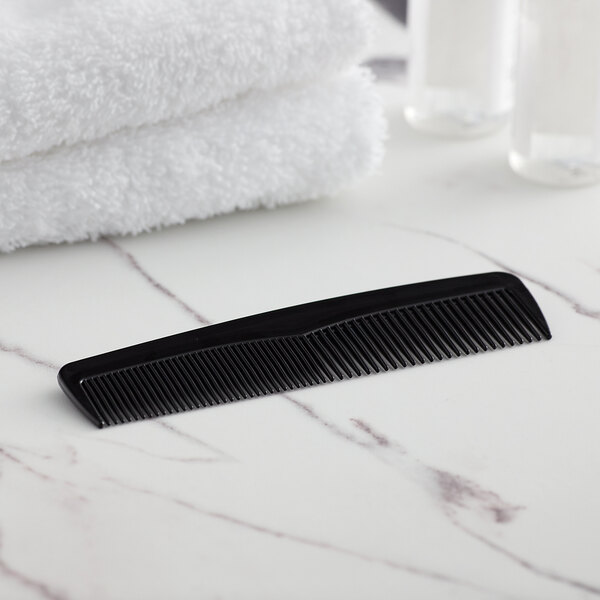 A black comb on a marble surface.