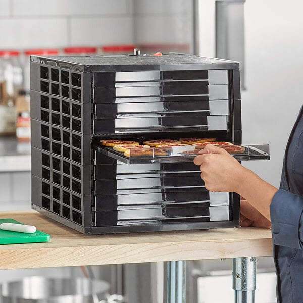 A woman putting food into a tray in a Backyard Pro food dehydrator.