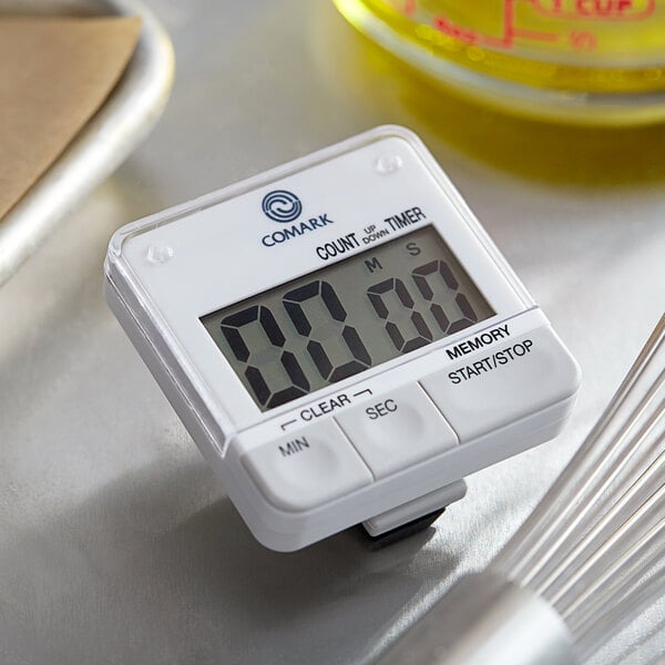 A white Comark digital kitchen timer on a counter.