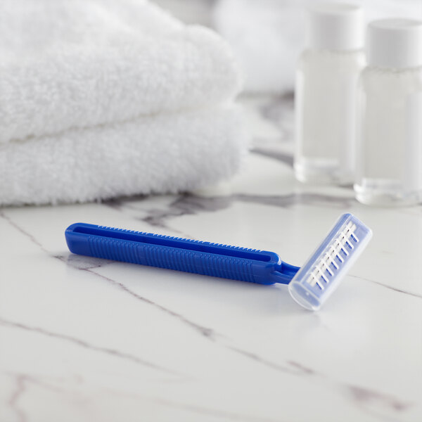 A blue Novo Essentials twin blade disposable razor on a marble surface.