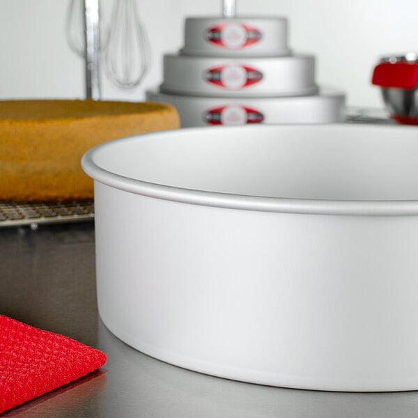 A Fat Daddio's round anodized aluminum cake pan on a white counter.