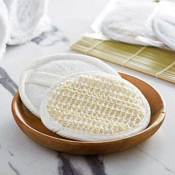 A wooden bowl filled with round white Novo Essentials bath loofahs.