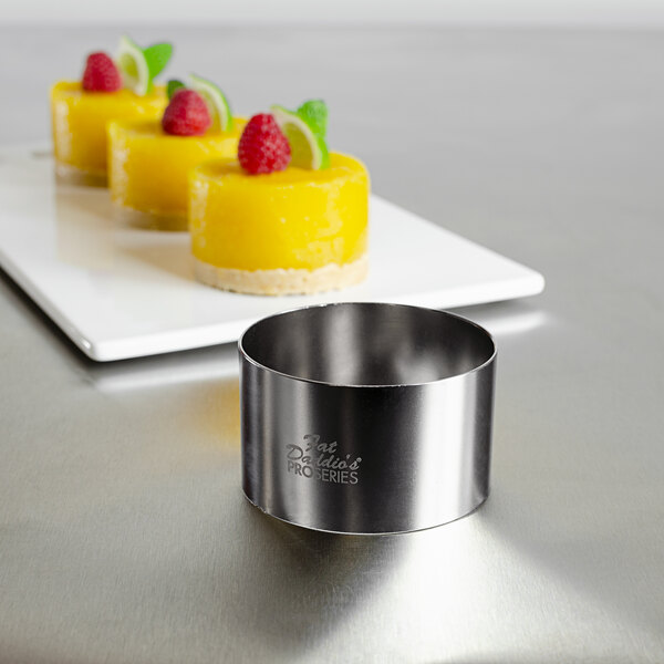 A Fat Daddio's stainless steel round cake ring with fruit on top.