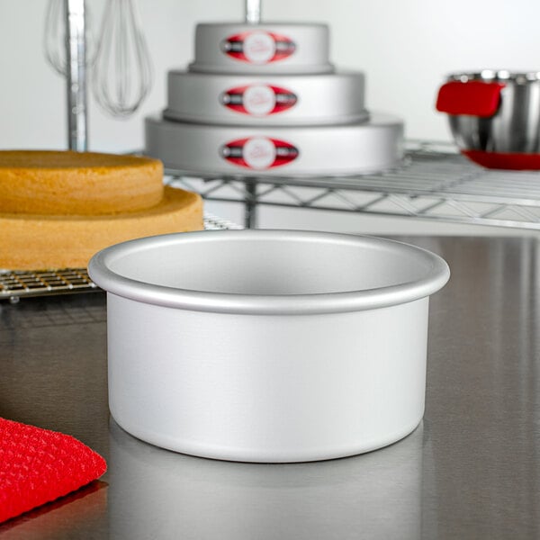 A Fat Daddio's round anodized aluminum cake pan on a white table with a red and white striped cloth.