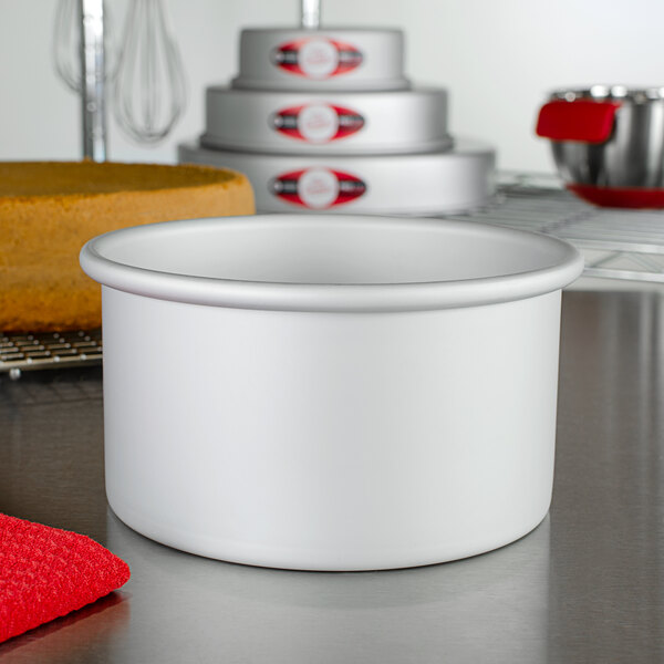A Fat Daddio's round anodized aluminum cake pan on a white counter.
