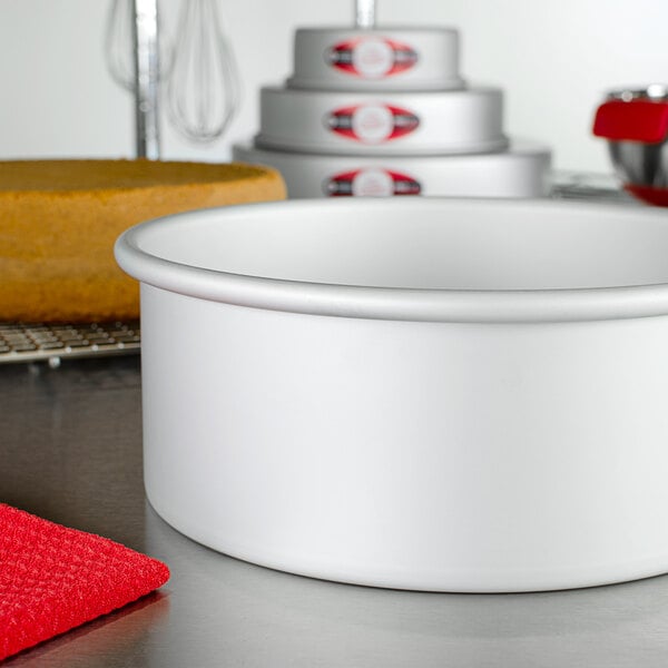 A round anodized aluminum cake pan on a white counter.
