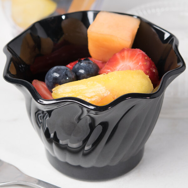 A black Cambro Camwear swirl bowl filled with fruit on a table.