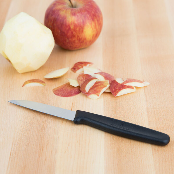 A Victorinox sheep's foot paring knife next to a sliced apple on a table.