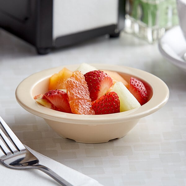 A bowl of fruit on a table in a white melamine bowl.
