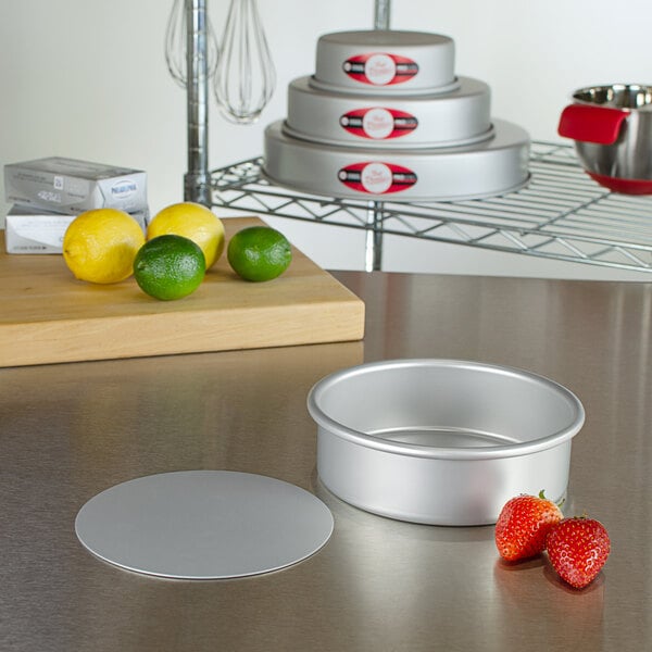 A round silver Fat Daddio's cheesecake pan on a countertop next to strawberries.