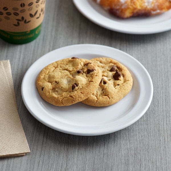 An Acopa Foundations white melamine plate with two chocolate chip cookies and a cup of coffee on a table.