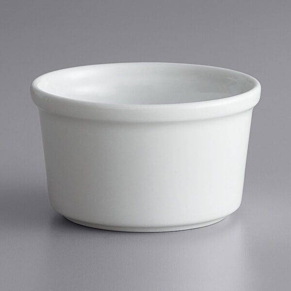 A close up of a bright white porcelain ramekin on a gray surface.