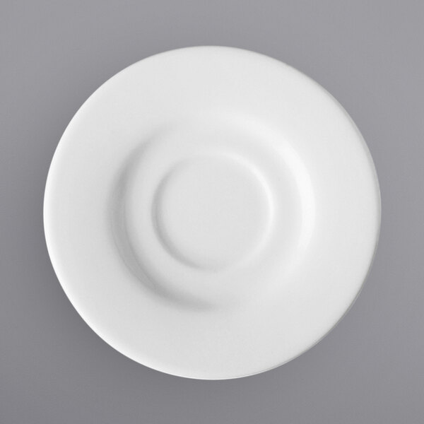 A close-up of a bright white porcelain tea / bouillon saucer with a circular pattern in the middle.