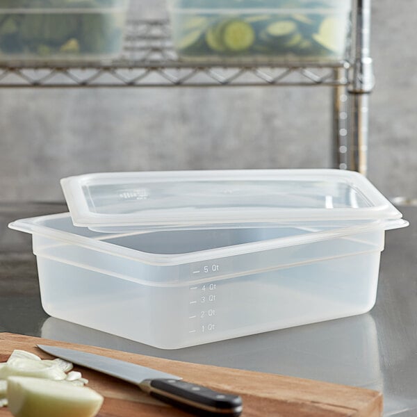 A Cambro translucent polypropylene food pan with a seal lid on a counter with other plastic containers.