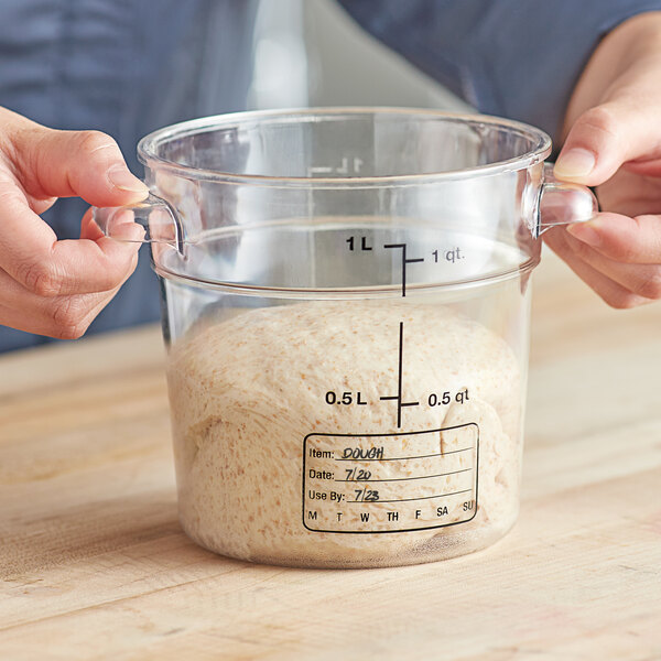 A person holding a measuring cup with white flour in it.