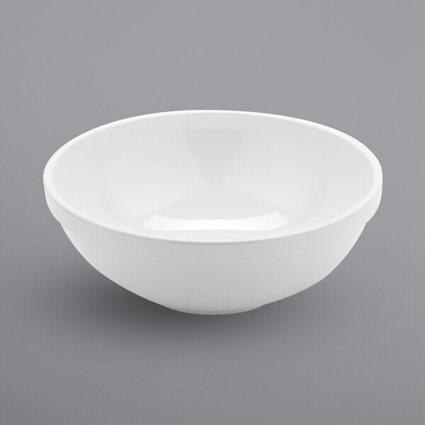 A white GET Settlement melamine bowl on a gray surface.