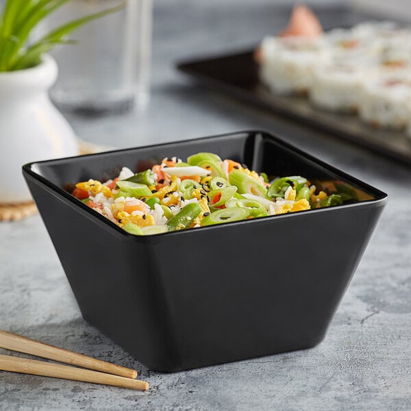 A black Acopa Rittenhouse square melamine bowl filled with food and chopsticks.