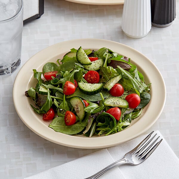 An Acopa tan melamine plate with a salad of tomatoes, cucumbers, and spinach on it.