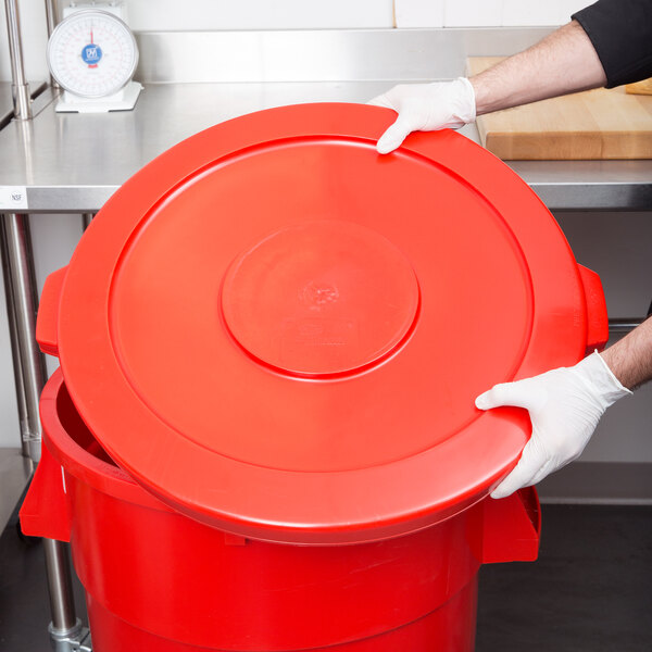 A person in gloves holding a red lid for a Continental 44 gallon trash can.