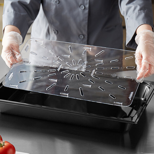 A person in a chef's coat using a Vigor clear polycarbonate drain tray on a counter in a salad bar.