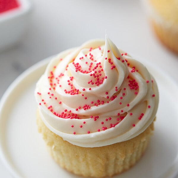 A close up of a cupcake with white frosting and pink sprinkles.