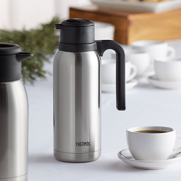 A silver stainless steel Thermos carafe with a black twist top.