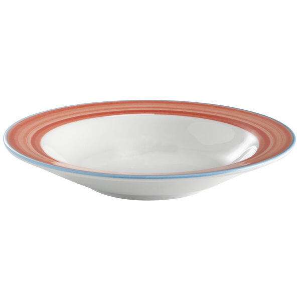 A close-up of a white Corona porcelain soup bowl with a coral and blue stripe on the rim.