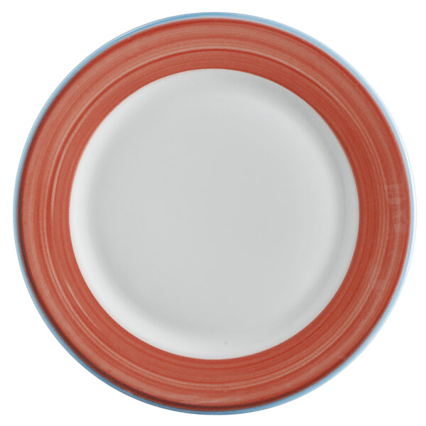 A close-up of a white porcelain plate with a red rim and coral and blue designs.