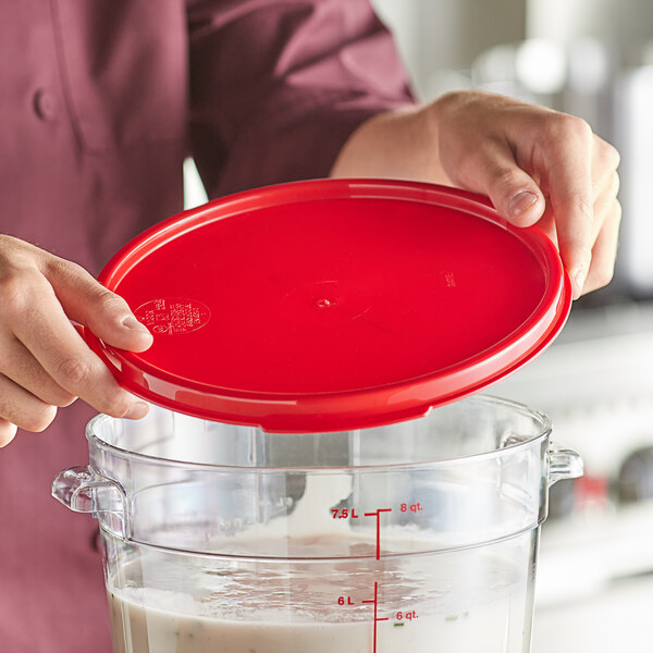 A woman holding a red Vigor food storage container lid over a clear container.
