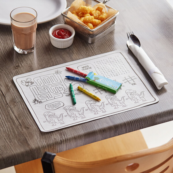 A table with food, a Choice Kids Dinosaur placemat, and colored pencils.