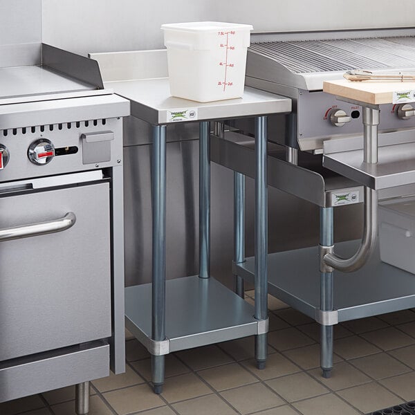 A Regency stainless steel equipment filler table with a backsplash and undershelf in a kitchen with a stove and sink.