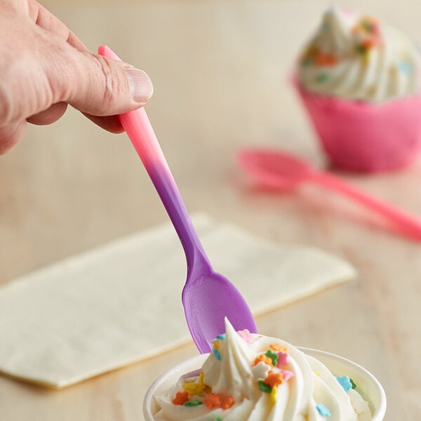 A hand using a pink to purple color-changing dessert spoon to eat ice cream.