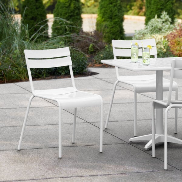 A white Lancaster Table & Seating outdoor side chair and table set on a patio.