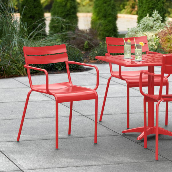 A red Lancaster Table & Seating outdoor arm chair at a table on a patio.
