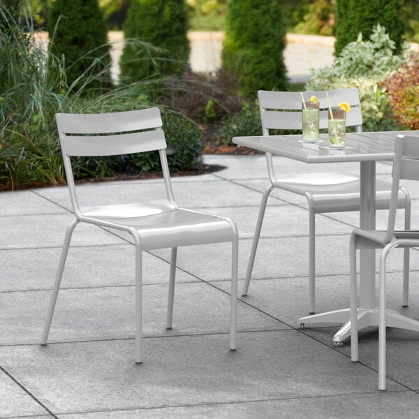 A white Lancaster Table & Seating outdoor side chair on a patio.