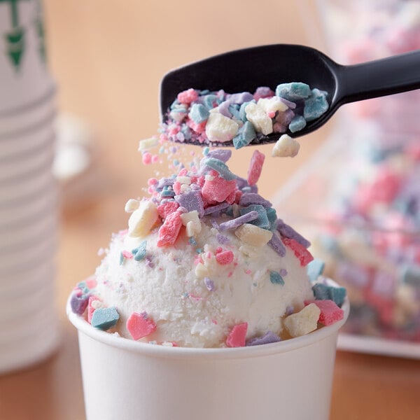 A white scoop of Unicorn Bark topping on a scoop of ice cream.