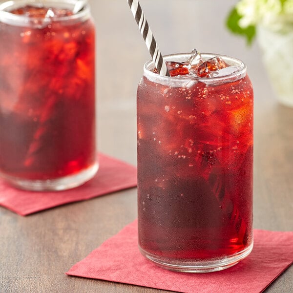 A glass jar filled with Boylan Black Cherry soda with a straw in it.