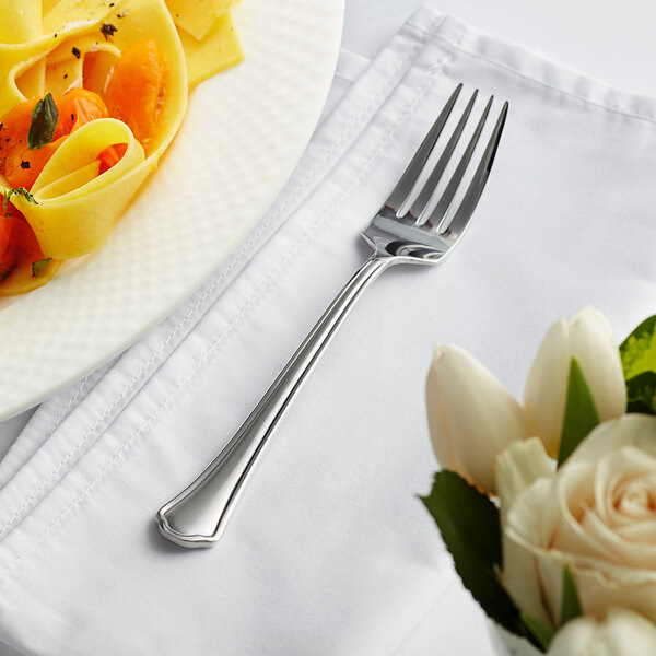 An Acopa stainless steel dinner fork on a white plate next to pasta.