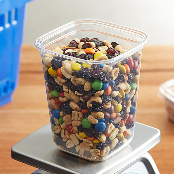 A Fabri-Kal plastic deli container filled with nuts and candies.