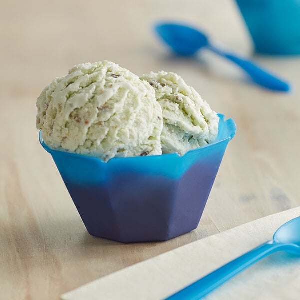 A blue dessert cup filled with ice cream with a spoon in it.