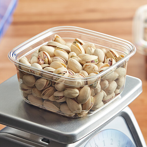 A bowl of shelled pistachios in a Fabri-Kal square deli container.