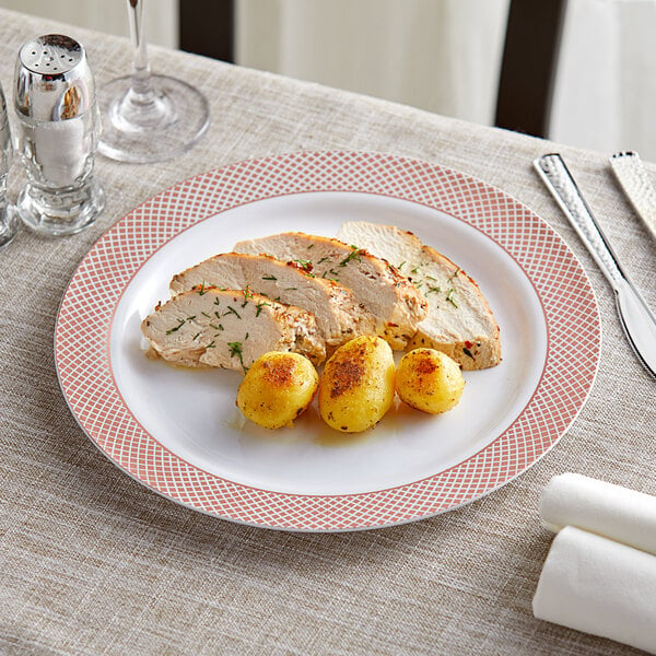A Visions white plastic plate with rose gold lattice design holding chicken and potatoes.