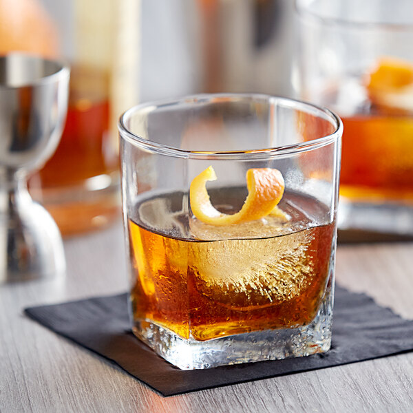 An Anchor Hocking Rio Rocks Glass with whiskey, ice, and an orange peel.