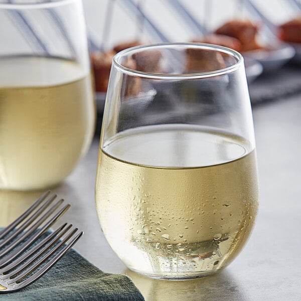 A close-up of a glass of white wine next to a fork.