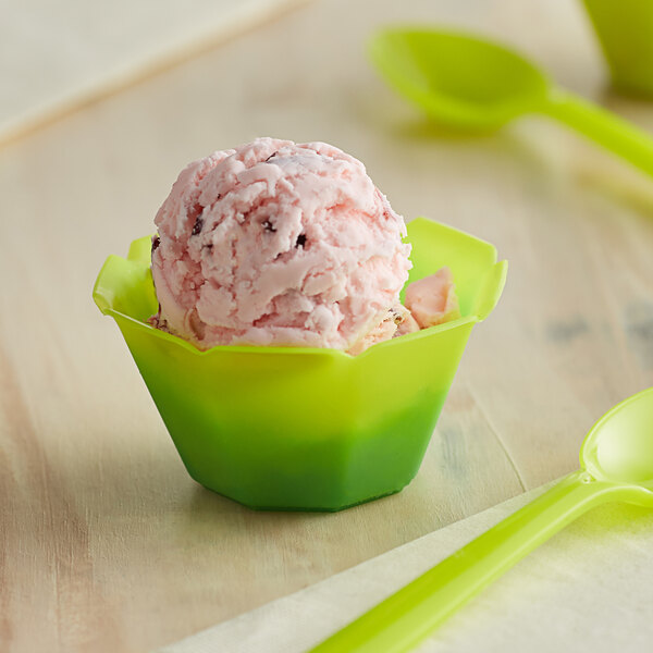 A scoop of ice cream in a green color-changing dessert cup with a green spoon.