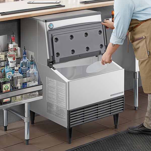A man standing next to a Hoshizaki undercounter ice machine on a counter.