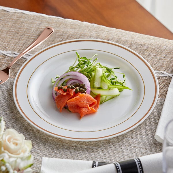 A Visions white plastic plate with rose gold bands holding salmon and vegetables on a table.